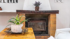 A wooden table with a woven basket containing a plant, a fireplace with a mantel, and abstract wall art. - Holiday Home in Es Cami Vell with Pool and Wi-Fi (INCA)
