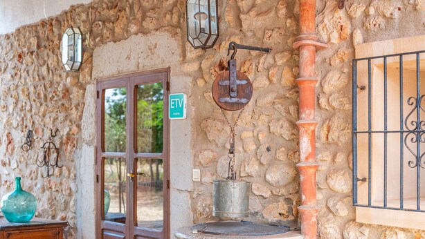 A stone wall with a metal water spigot, a wooden door, and a green sign. - Holiday Home in Es Cami Vell with Pool and Wi-Fi (INCA)