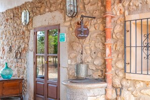 Mur de pedra amb un aireig metàl·lic, una porta de fusta i un senyal verd.