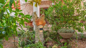 A garden with various plants, a rustic tree stump, and a metal planter. - Holiday Home in Es Cami Vell with Pool and Wi-Fi (INCA)