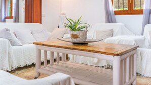 A room with white furniture, a small wooden table with a plant, and a window with curtains. - Holiday Home in Es Cami Vell with Pool and Wi-Fi (INCA)