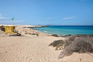 A beach with a lifeguard tower, sandy shore, and clear blue water.