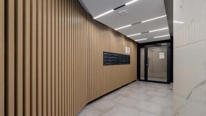 Un pasillo moderno con paneles de madera verticales, un tablero informativo negro y un suelo de mármol.