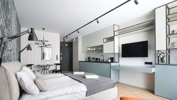 Habitación de hotel moderna con cama, escritorio y kitchenette.