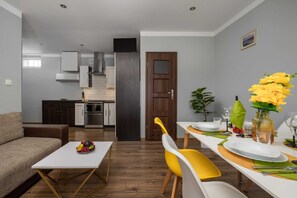 A modern living room with a sofa, dining table, and kitchen in the background.