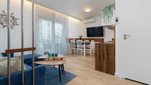 Un salon moderne avec un canapé bleu, une table basse en bois et un coin repas avec des chaises blanches.