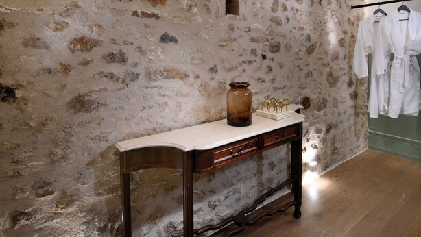 Un muro in pietra con una panca di legno e un appendiabiti a parete.