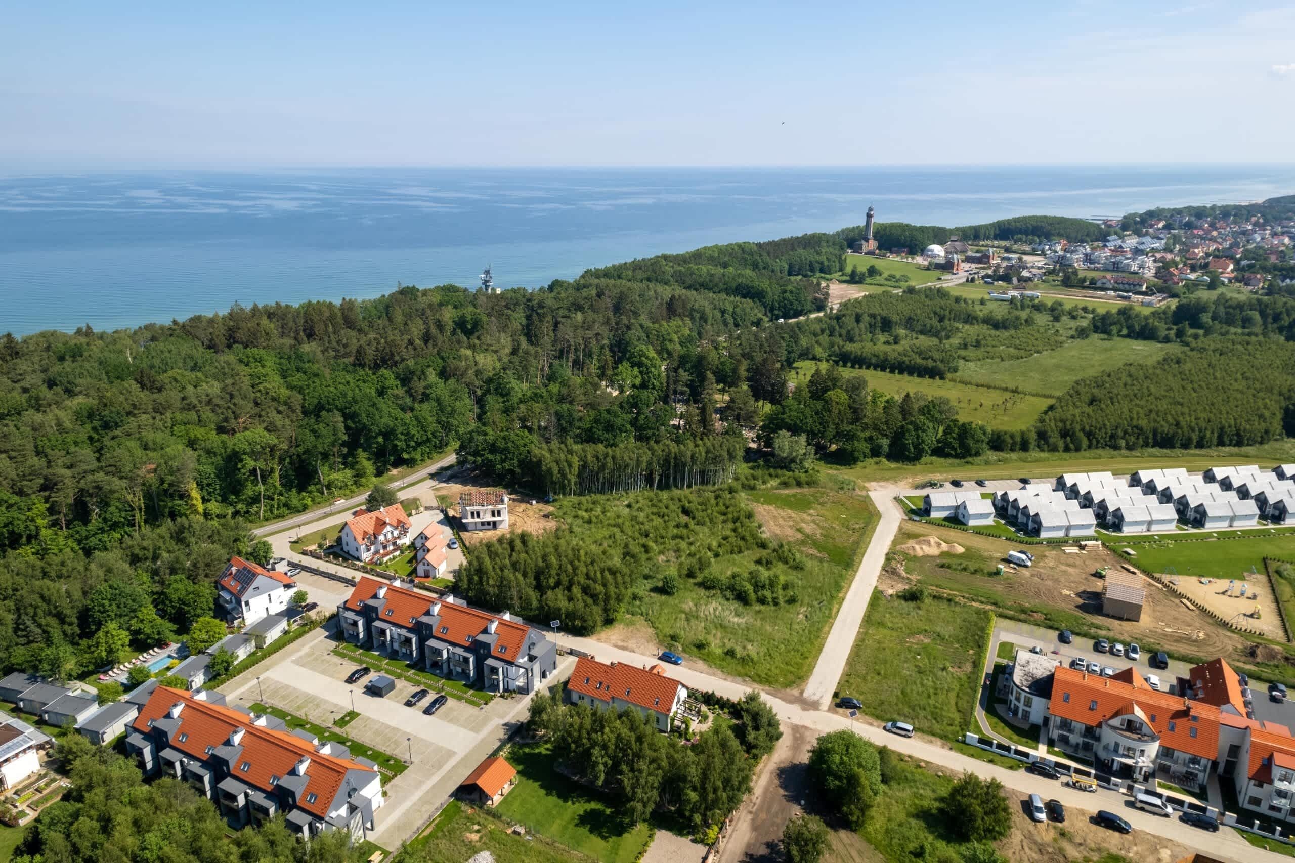 An aerial view of a residential area with houses, a lighthouse, and a body of water.