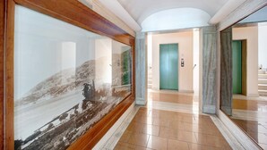 A hallway with a large framed photograph, a green door, and a marble floor.