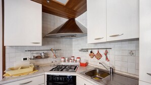 A kitchen with white cabinets, a stainless steel sink, a gas stove, and a built-in oven.