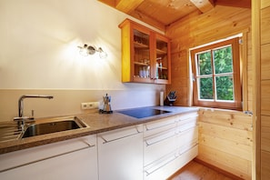 A kitchen with a granite countertop, stainless steel sink, wooden cabinets, and a window with a view of greenery. - Chalet 'Bergchalet Refugium Martius' with Mountain View, Garden & Wi-Fi (Marlengo)