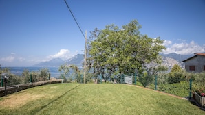 Un prato verde con vista sul mare e sulle montagne.