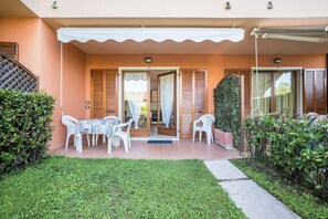 A building with a covered patio, a table with chairs, and a door leading to an interior space.