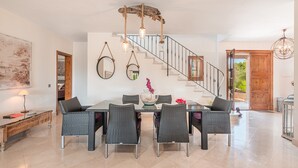 Un comedor amplio con techo alto, una escalera y vistas al exterior.