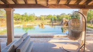 Un espacio exterior cubierto con piscina, una silla de mimbre y un banco.