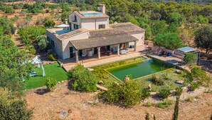 Una villa con piscina, patio y vistas del paisaje circundante.
