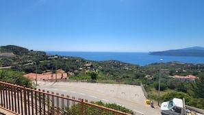 A coastal road with a clear view of the sea and hills.