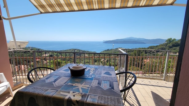A table with a starfish design, a cup, and a view of the sea and hills.