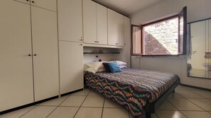 A bedroom with a bed, a wardrobe, a window with a view, and tiled flooring. - Apartment "Bellavista" with Sea View, Private Balcony and Terrace (Capoliveri)