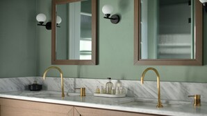 A bathroom with a marble sink, gold faucets, and a mirror above the sink.