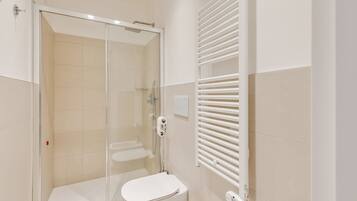 A modern bathroom with a glass-enclosed shower, a white toilet, and a towel rack.