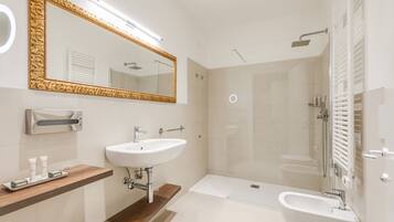 A modern bathroom with a large mirror, two sinks, a bathtub, and a shower.