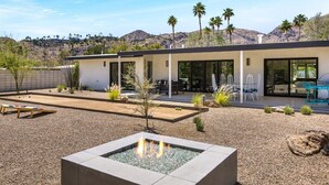 Une maison moderne dotée d’un patio, d’un espace salon extérieur et d’un foyer.