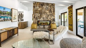 Un salon moderne avec une cheminée en pierre, une table basse en verre et un canapé.