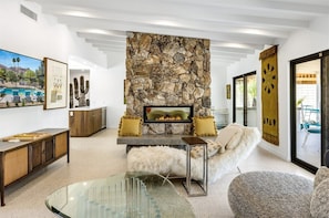 A modern living room with a stone fireplace, a glass coffee table, and a sofa.