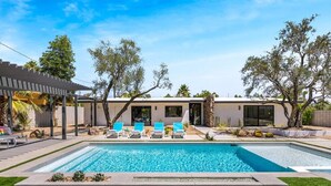 Une maison moderne dotée d’une piscine, d’un espace salon extérieur et d’une pergola.