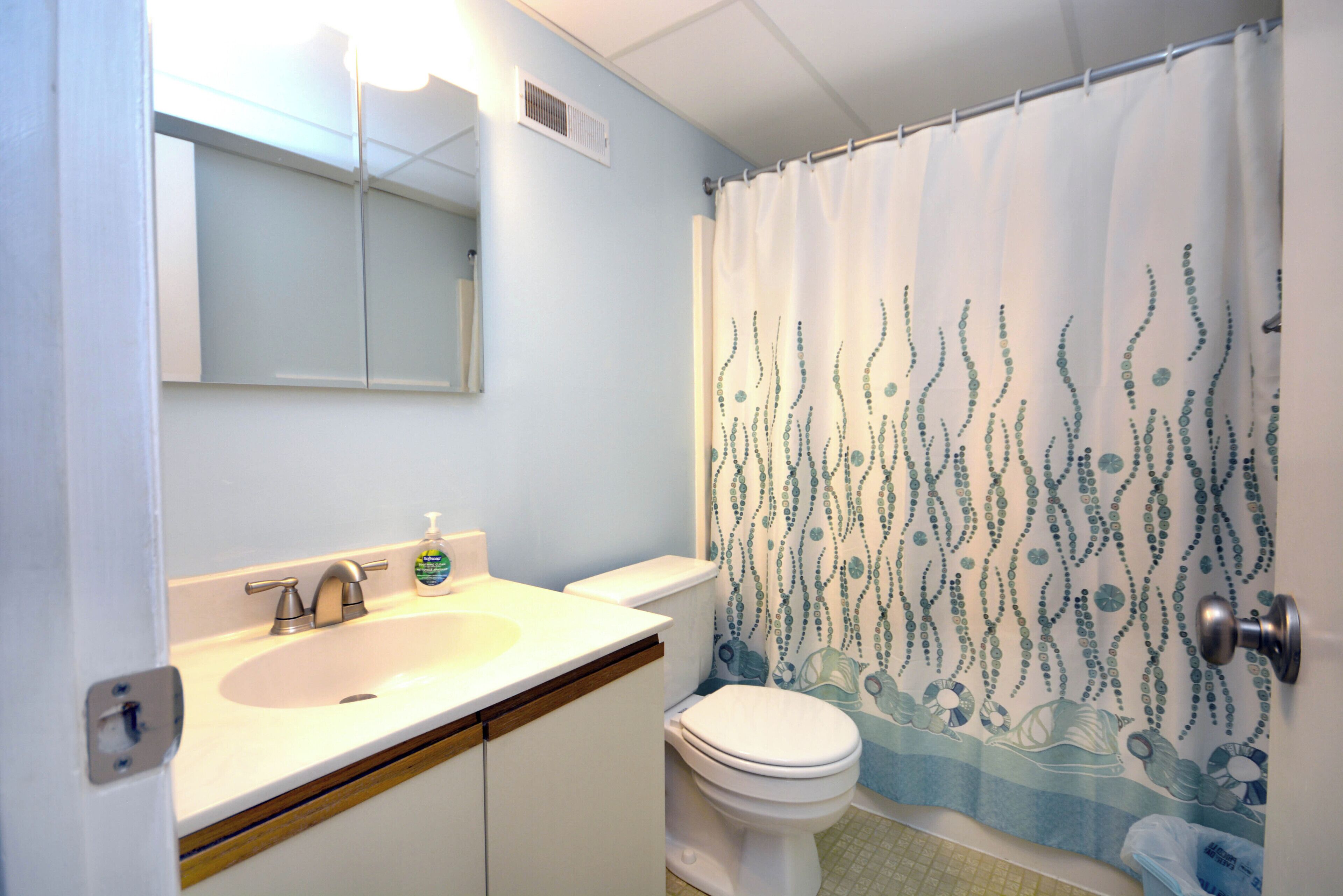 Un baño con lavamanos, inodoro y cortina de ducha.