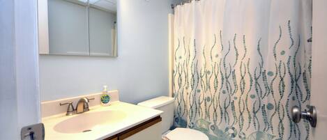 Un baño con lavamanos, inodoro y cortina de ducha.