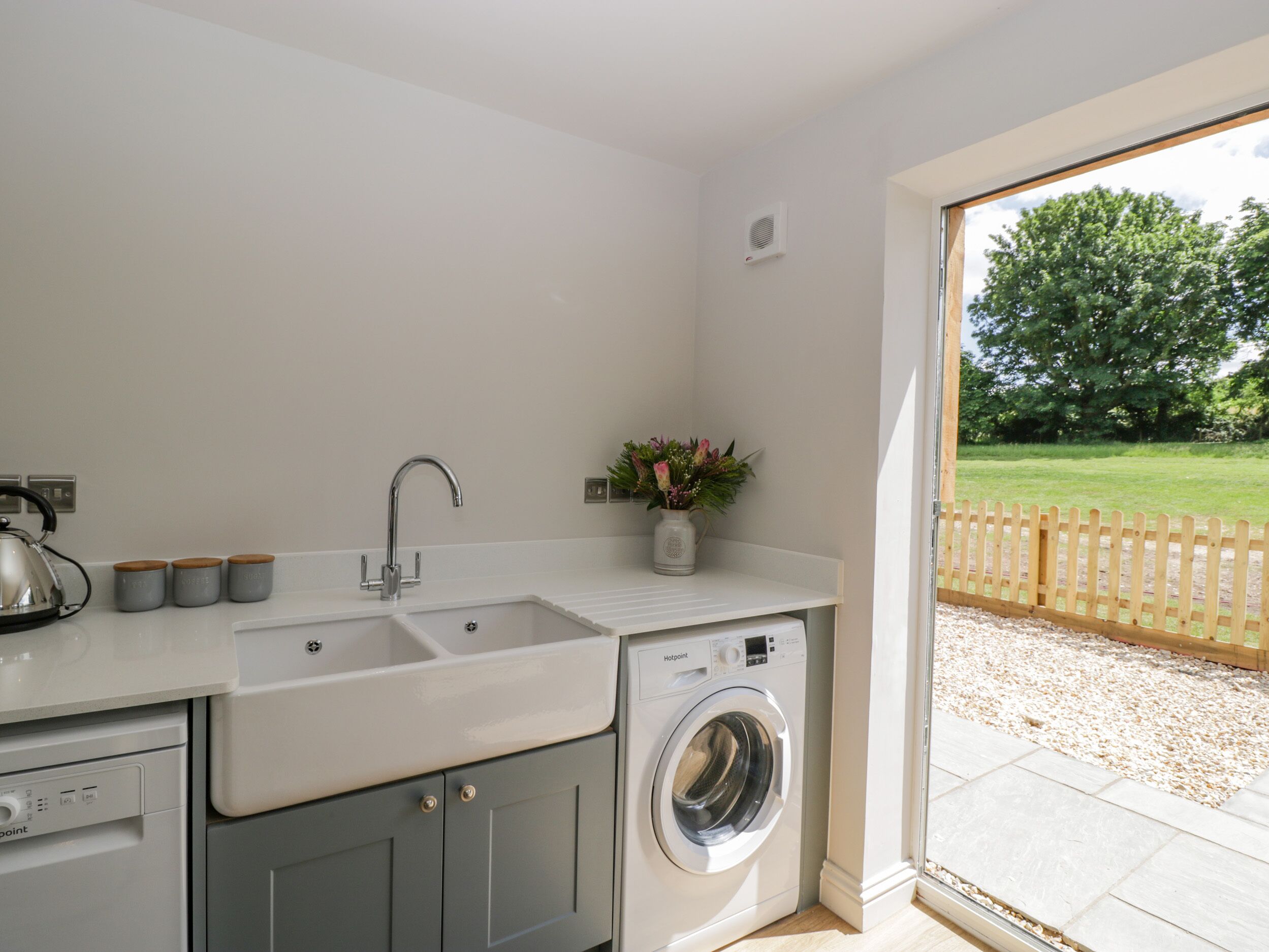 A compact kitchen with a sink, kettle, and a washing machine.