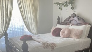 Een slaapkamer met een houten bed, wit beddengoed en een zacht, wit vloerkleed.