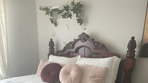 Een keurig opgemaakt bed met een witte quilt, meerdere kussens en een decoratief hoofdbord.