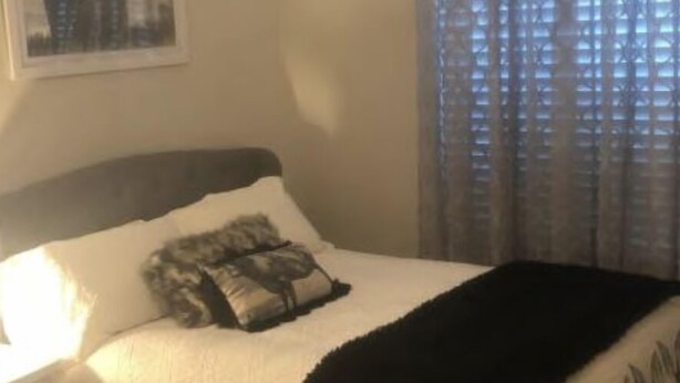 Een slaapkamer met een bed, kussens en een raam met gordijnen.