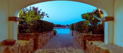 A stone pathway leading to a pool with a clear view of the water and surrounding greenery.