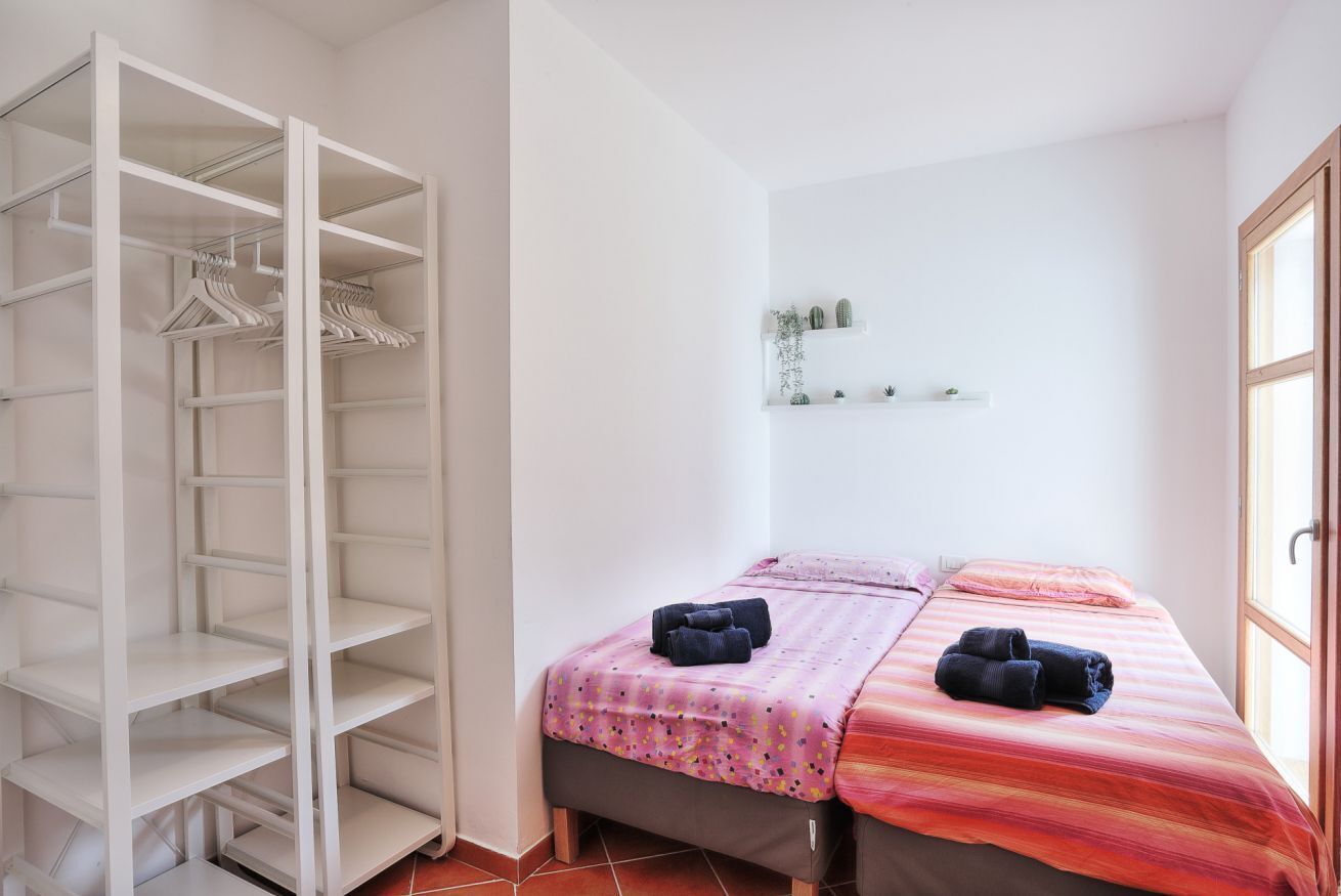 Un dormitorio con cama, armario y estante con plantas.