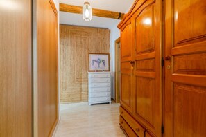 A hallway with wooden doors, a white dresser, and a hanging light fixture.