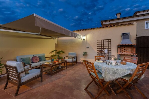 Un patio al aire libre con un sofá, sillas, una mesa y un horno de ladrillo.