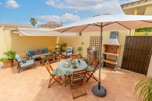 An outdoor patio with a round table, chairs, a sofa, and a grill.
