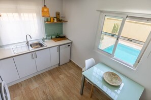 A compact kitchen with a sink, dishwasher, and a window overlooking a pool.