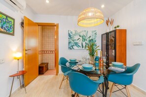 Un comedor con una mesa de vidrio, sillas azules y una lámpara colgante.
