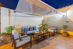 Un espace extérieur aménagé avec un canapé, des fauteuils, une table basse et des plantes en pot.