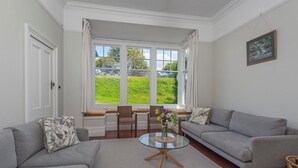 A living room with two grey sofas, a glass coffee table, and a large window with a view of greenery. - Lynmouth Cottage - a cosy home away from home (New Town)