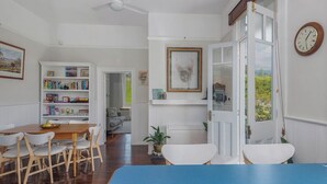 A dining area with a wooden table and chairs, a bookshelf, a ceiling fan, and a view through a door. - Lynmouth Cottage - a cosy home away from home (New Town)