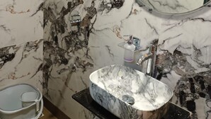 A bathroom with a marble sink, a round mirror, and a towel rack. - HOTEL AIRPORT ANNEX (Mumbai)