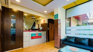 A hotel lobby with a reception desk labeled "Airport Annex," a sofa, and a coffee table with newspapers. - HOTEL AIRPORT ANNEX (Mumbai)