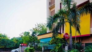 A multi-story building with a yellow facade, palm trees, and a red sign. - HOTEL AIRPORT ANNEX (Mumbai)