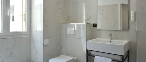 A modern bathroom with a toilet, bidet, and sink.